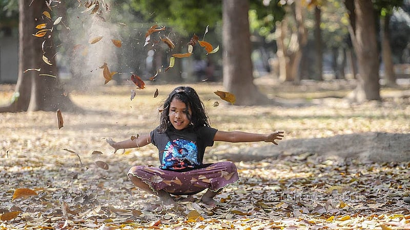 A child plays with fallen leaves in Ramna Park on Tuesday, Mar 4, 2025. Photo: Abdullah al Momin