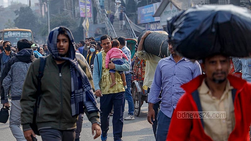 A man carrying a child walks past the blocked Science Laboratory intersection in Dhaka on Thursday, Jan 15, 2026. Photo: Mahmud Zaman Ovi