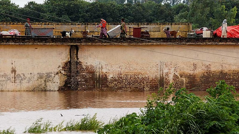 A family with their belongings takes refuge over a roof of their house near Chenab River, following the monsoon rains and rising water level in Wazirabad, in Punjab province, Pakistan Aug 27, 2025. REUTERS/Akhtar Soomro