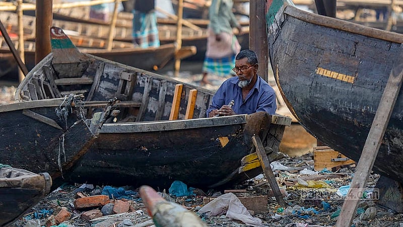 A shipwright works on fixing boats along the Buriganga. It takes him two to three days to repair each boat. Photo: Mahmud Zaman Ovi