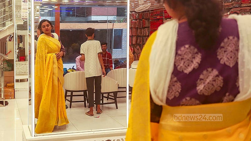 A woman tries on a saree during Eid shopping at the Adi Indian Silk House at Benarasi Palli in Dhaka’s Mirpur. Photo: Abdullah al Momin