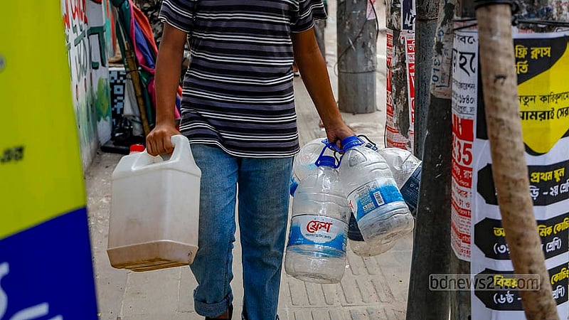 A man carries plastic containers to collect purified water from a water ATM booth in Dhaka's Banasree. Photo: Mahmud Zaman Ovi