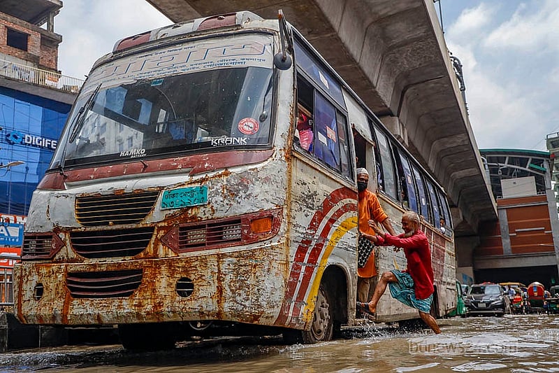 A person rushes to board a bus on a road inundated by heavy rain in Mirpur on Sunday, Aug 17, 2025. Photo: Mahmud Zaman Ovi