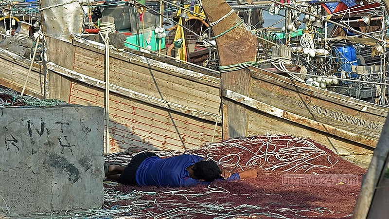 A worker falls asleep in the heat while repairing nets in Chattogram’s Fisheryghat area. Photo: Suman Babu