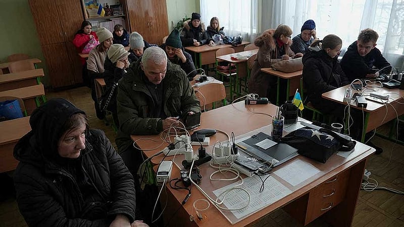 Residents wait while charging their devices inside a school classroom turned into a humanitarian aid point during a power blackout after critical civil infrastructure was hit by recent Russian missile and drone strikes, amid Russia's attack on Ukraine, in Kyiv, Ukraine Jan 11, 2026. REUTERS/Anna Voitenko
