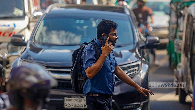 In Dhaka, pedestrians are often seen crossing busy roads without obeying traffic signals, with mobile phones pressed to their ears. Photo: Mahmud Zaman Ovi