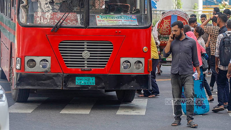In Karwan Bazar, a man crosses a busy road with his attention fixed on his mobile phone as a bus comes up behind him. Photo: Mahmud Zaman Ovi
