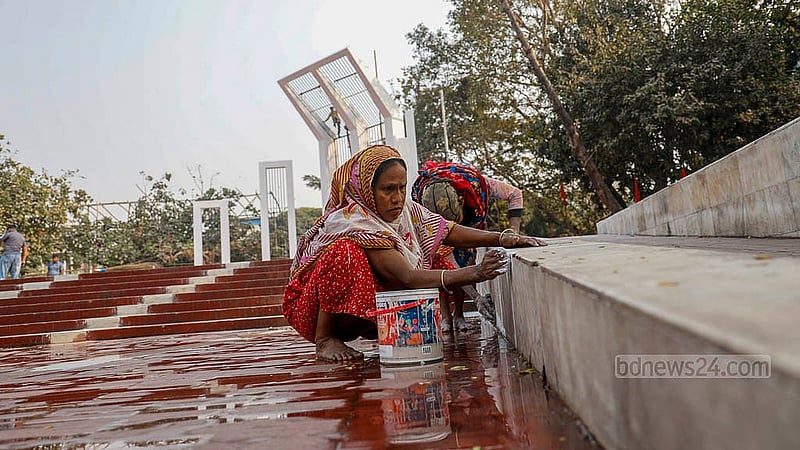 Two female workers scrub the base of the Central Shaheed Minar, giving it a fresh look before International Mother Language Day. Photo: Mahmud Zaman Ovi