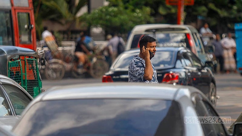 A man crosses a busy road while talking on his mobile phone in Dhaka’s Karwan Bazar on Tuesday, Aug 19, 2025. Photo: Mahmud Zaman Ovi