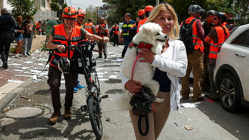 A woman carries a dog at an impact site, following a barrage of missiles launched from Iran, amid the U.S.-Israeli conflict with Iran, in Ramat Gan, Israel, April 4, 2026. Photo: Reuters