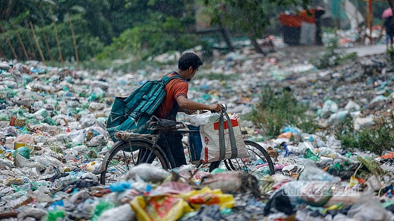 The waste is so densely packed in the Shubhadda Canal in Dhaka’s South Keraniganj that a man is carrying his cycle across it. Photo: Mahmud Zaman Ovi