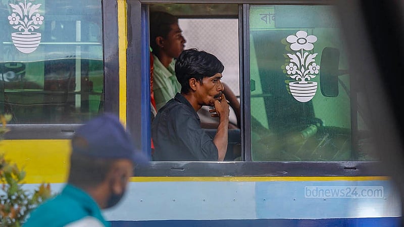 The driver of an Ayat Paribahan bus smokes while driving, with traffic police standing nearby at the Karwanbazar intersection on Sunday, Sept 28, 2025. There is no compliance with the smoking ban. Photo: Mahmud Zaman Ovi