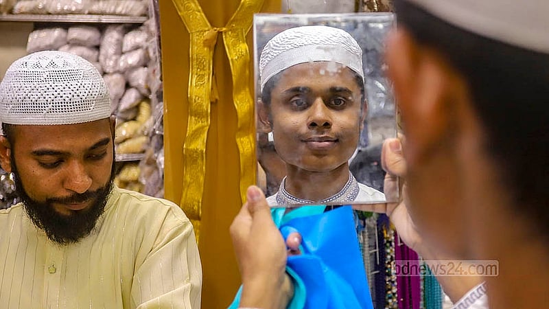 Along with other items of clothing, the demand for skull caps is high in shops near the Baitul Mukarram National Mosque ahead of Eid ul-Fitr. Some are trying the caps on if they like the designs. Photo: Abdullah al Momin