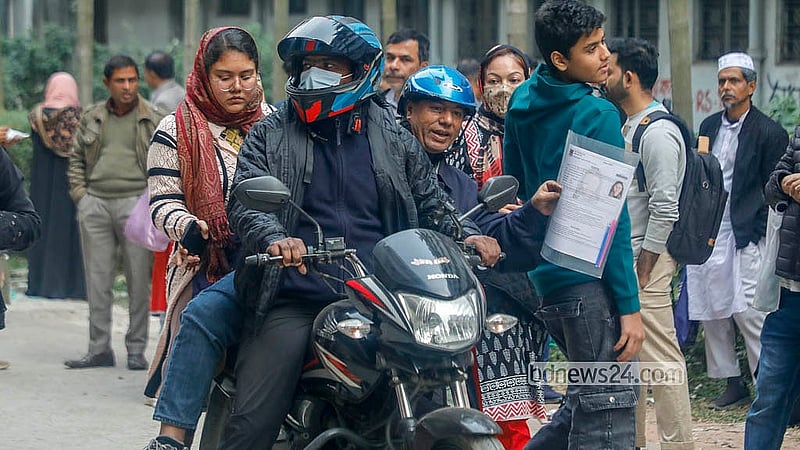 Heavy traffic on the day of the Dhaka University Faculty of Science admission test for the 2025–26 academic year forced many students to seek alternative transport on Saturday, Dec 27, 2025. A father gets off a bus at Karwan Bazar and takes his child to the exam venue on a ride-sharing bike. Photo: Abdullah Al Momin
