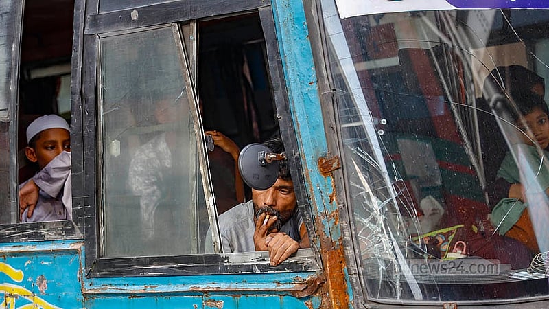A child in the back seat covers their face to avoid cigarette smoke, while the driver pays no attention. The driver of a Tanjil Paribahan bus is smoking at the Karwanbazar intersection in Dhaka on Sunday, Sept 28, 2025. Photo: Mahmud Zaman Ovi