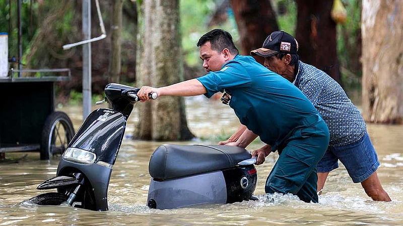 A paramilitary officer and a man remove a motorcycle from a flooded area after Typhoon Bualoi made landfall in Nghe An province, Vietnam, Sept 30, 2025. REUTERS/Thinh Nguyen