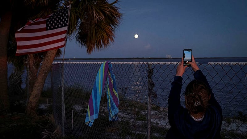 A woman uses her phone to take photos of the moon after the launch of the next-generation moon rocket, the Space Launch System (SLS) rocket and the Orion crew capsule, part of NASA's Artemis II lunar flyby mission, from NASA's Kennedy Space Center, in Titusville, Florida, U.S., April 1, 2026. Photo: Reuters