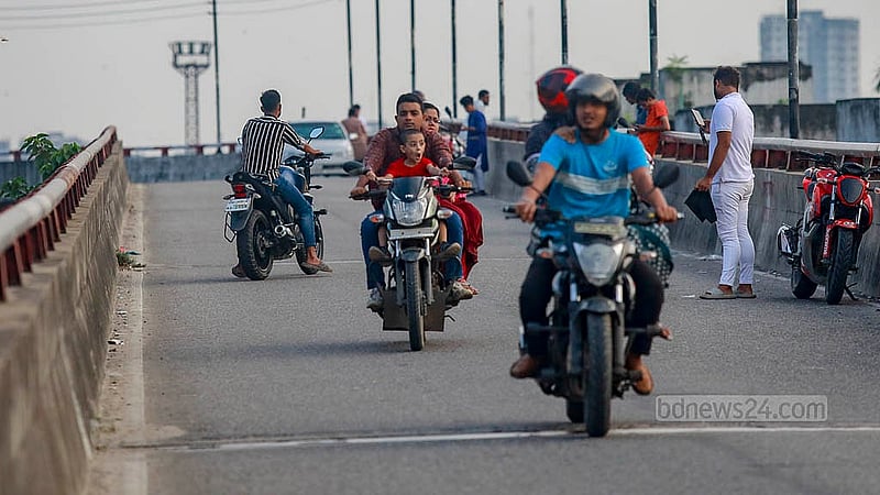 Three people, including a child, ride on a motorcycle over Dhaka’s Khilgaon flyover. None of them are wearing helmets, and the child is seated at the front of the bike. Photo: Mahmud Zaman Ovi