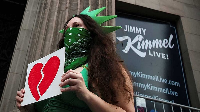 A woman wears a Statue of Liberty costume as she holds an image of a broken heart, outside the El Capitan Entertainment Centre, where &amp;quot;Jimmy Kimmel Live!&amp;quot; is recorded for broadcast, on Hollywood Boulevard in Los Angeles, California, US Sept 17, 2025. REUTERS/Daniel Cole