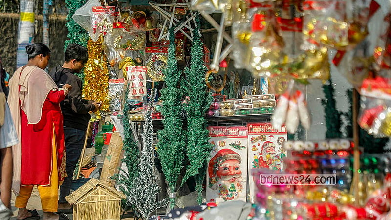 A shopkeeper holds a Christmas tree for sale outside the Holy Rosary Church in Dhaka. The trees, available in different sizes, are priced between Tk 200 and Tk 4,000. Photo: Abdullah Al Momin
