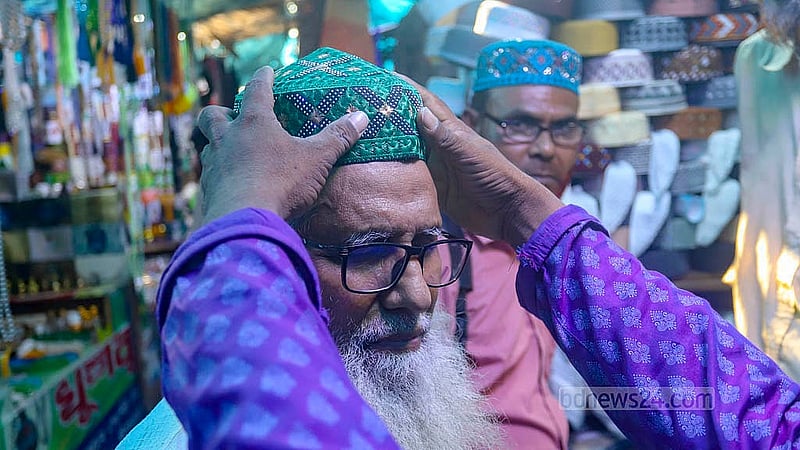 Along with other items of clothing, the demand for skull caps is high in shops near the Baitul Mukarram National Mosque ahead of Eid ul-Fitr. Some are trying the caps on if they like the designs. Photo: Abdullah al Momin