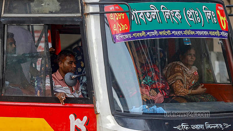 A female passenger sits next to the bus driver, who keeps a cigarette hidden from view. Passenger discomfort is often disregarded. Photo: Mahmud Zaman Ovi