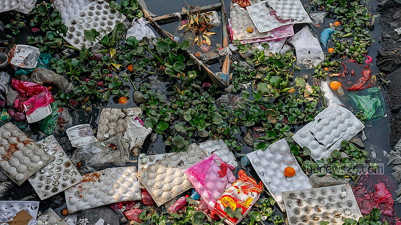 The water level in the Buriganga River drops sharply during the dry winter season, letting the layers of plastic and other wastes surface. The owners of makeshift shops at the launch terminal throw their garbage in the river. Photo: Mahmud Zaman Ovi
