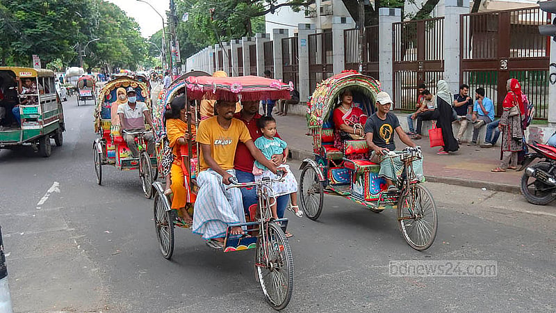 Two passengers sit on the back, while another sits next to the driver on a battery-powered rickshaw. The arrangement has the driver bending uncomfortably to steer the vehicle. Photo: Abdullah Al Momin