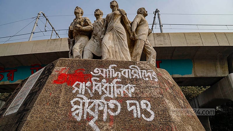 Students protesting the removal of images featuring the word “adivasi” – a collective term for a number of ethnic minority groups in Bangladesh – from textbooks wrote “grant adivasi people constitutional recognition” on the Raju Sculpture at Dhaka University on Wednesday, Jan 15, 2025. Photo: Mahmud Zaman Ovi