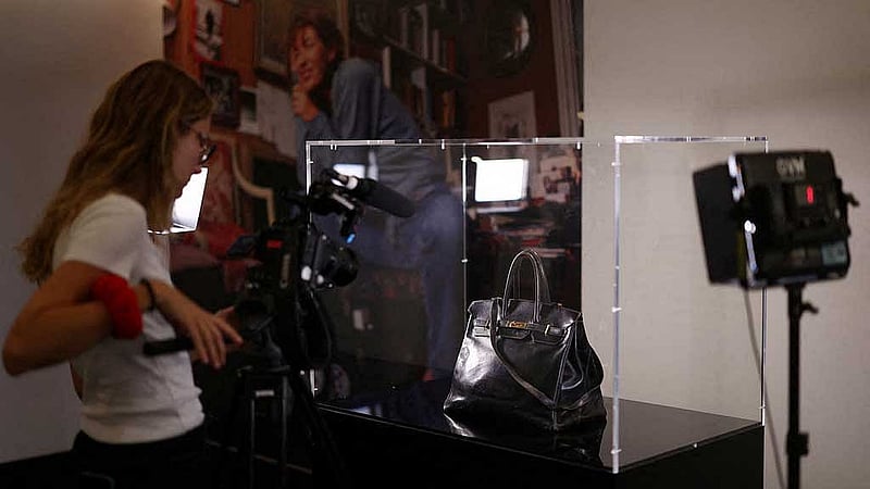 A camerawoman films the Original Birkin, the handbag crafted by French luxury fashion house Hermes for artist Jane Birkin and offered to her in 1985, displayed during a media preview of Sotheby's Paris Fashion Icons Sale at Sotheby’s auction house in Paris, France, Jul 2, 2025. REUTERS/Tom Nicholson