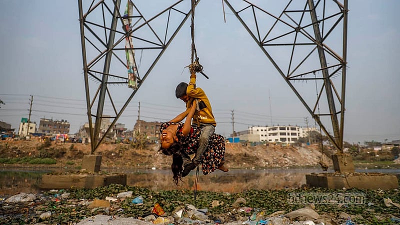 A branch of the Buriganga River flowing past Kamrangirchar lies choked with plastic and other pollutants. As winter sets in and water levels drop, the pollution becomes more visible, while a child swings from a rope tied to an electricity pole above the river. Photo:  Mahmud Zaman Ovi