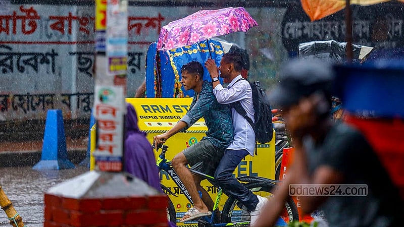 Two boys on a bicycle and with an umbrella enjoy their way through the rain at Mohammadpur bus stand in Dhaka on Monday, Jul 1, 2024. Photo: Mahmud Zaman Ovi