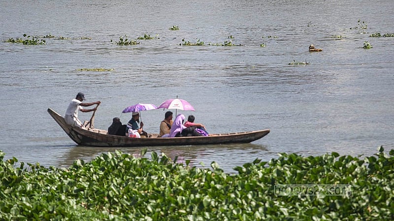 People seek shelter from the sun under umbrellas as they cross the river amid the intense early autumn heat in Old Dhaka’s Islambagh area. Photo: Abdullah al Momin