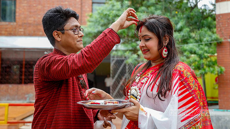 A husband applies vermillion – worn by the Goddess Durga on her feet - to the parting of his wife’s hair before they bid farewell to the Goddess Durga at Dhakeshwari Temple. Photo: Mahmud Zaman Ovi