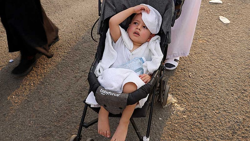 A child is pushed in a stroller during extremely hot weather, on the first day of the Satan stoning ritual, during the annual haj pilgrimage, in Mina, Saudi Arabia, June 16, 2024. REUTERS/Saleh Salem