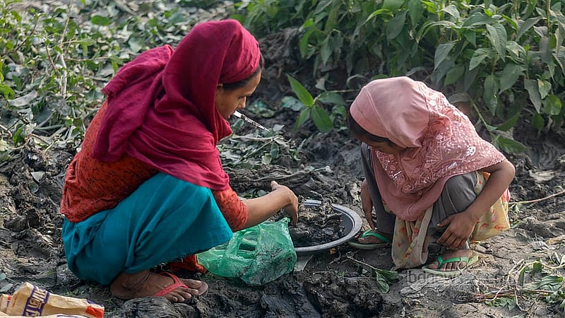 A woman gathers mud from the riverbank near Kamrangirchar Government Secondary School, which will later be used to make clay stoves.Photo: Mahmud Zaman Ovi