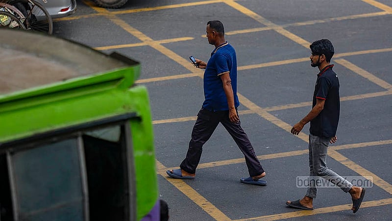 A man crosses a busy road in Dhaka’s Karwan Bazar while looking at his mobile phone. Photo: Mahmud Zaman Ovi