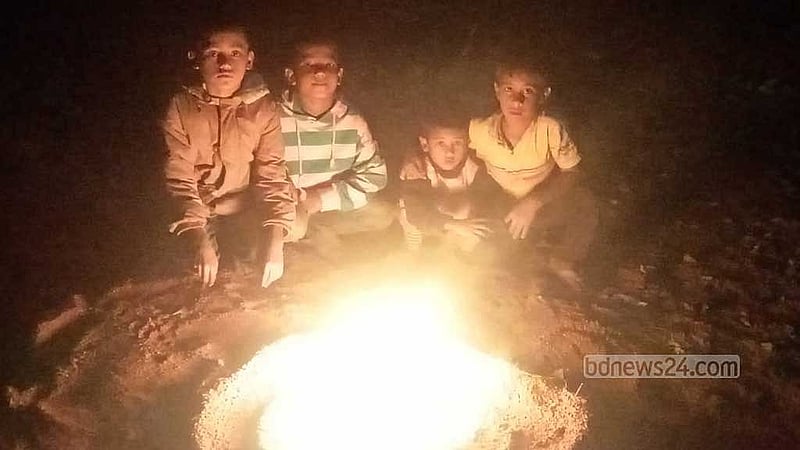 A group of four boys - (from left) Umor, Fahim, Noor, and Munna - gather around a fire to warm themselves up in Rangpur city on Monday, Jan 20, 2024.