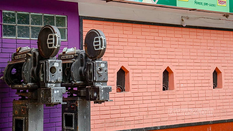 Old film equipment stands outside the gate of the BGB Cinema Hall, while a few staff members sit idly nearby. There are no crowds, no queues -only silence where moviegoers once gathered. Photo: Mahmud Zaman Ovi