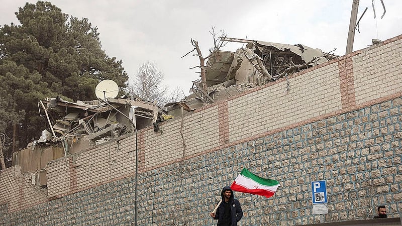 A man holds an Iranian flag near a destroyed state TV communications tower, following Israeli and U.S. strikes, amid the U.S.-Israel conflict with Iran, in Tehran, Iran, March 2, 2026. Photo: Reuters