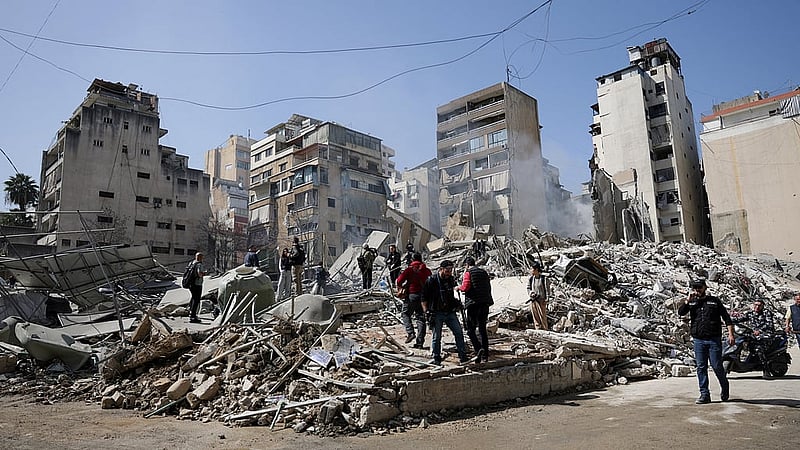 People walk amidst debris at the site of an Israeli strike, following an escalation between Hezbollah and Israel amid the US-Israeli conflict with Iran, Zuqaq al-Blat district in central Beirut, Lebanon, Mar 18, 2026. REUTERS/Khalil Ashawi