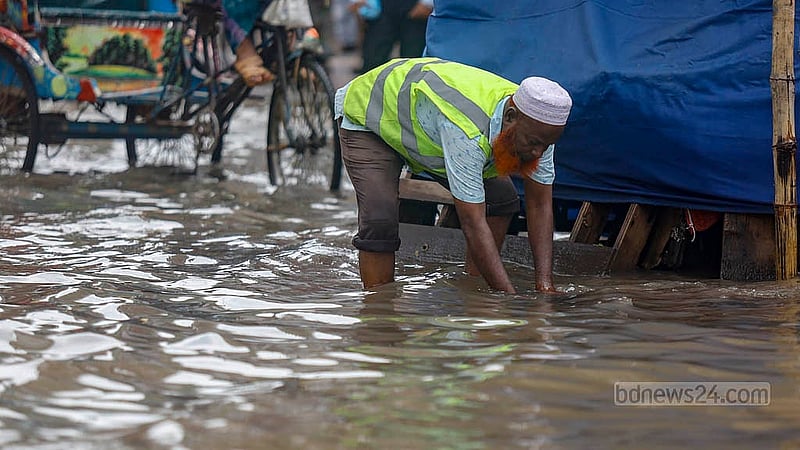 Dhaka North City Corporation workers clean dirt from manhole covers on a rain-submerged road in Mirpur on Sunday, Aug 17, 2025. Photo: Mahmud Zaman Ovi