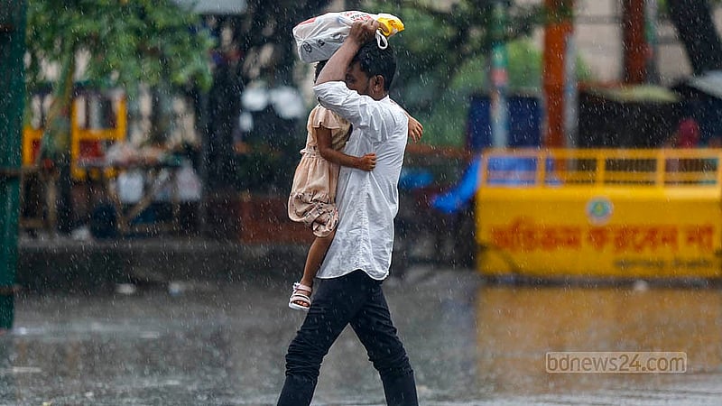 During heavy rain and the road blockade, a man tries to protect his child by holding up a plastic bag to cover their head. Photo: Mahmud Zaman Ovi