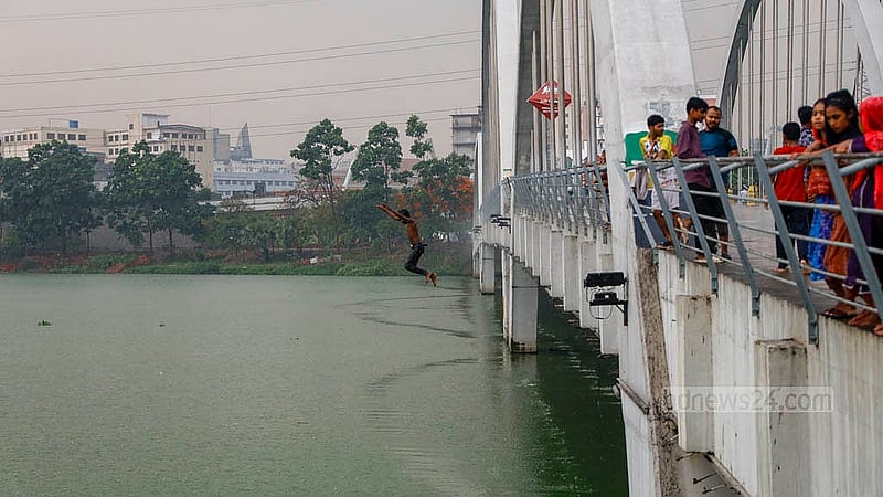 A child dives into the green and polluted waters of a lake in Hatirjheel amid the rain on Thursday, May 1, 2025. Photo: Mahmud Zaman Ovi