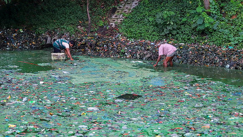 Two workers clean up garbage at Hatirjheel in Tejgaon's Kunipara. Photo: Abdullah Al Momin