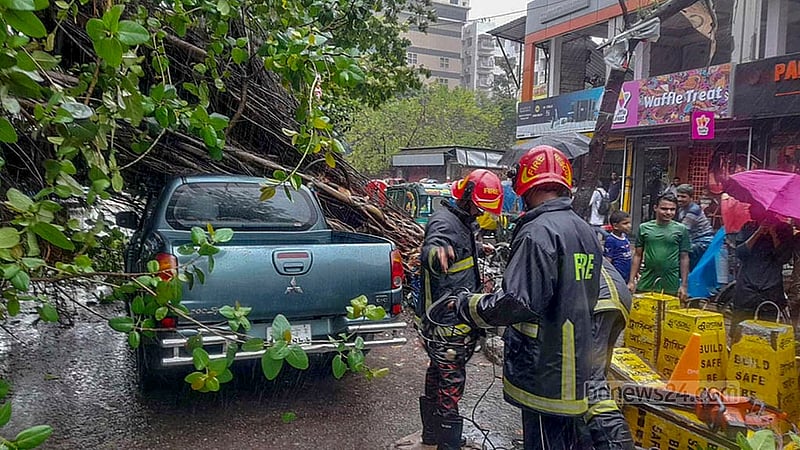 Fire Service workers conduct rescue operations on a car crushed by a falling tree in Dhaka’s Green Road area amid strong winds and heavy rain brought on by Cyclone Remal on Monday, May 27, 2024.