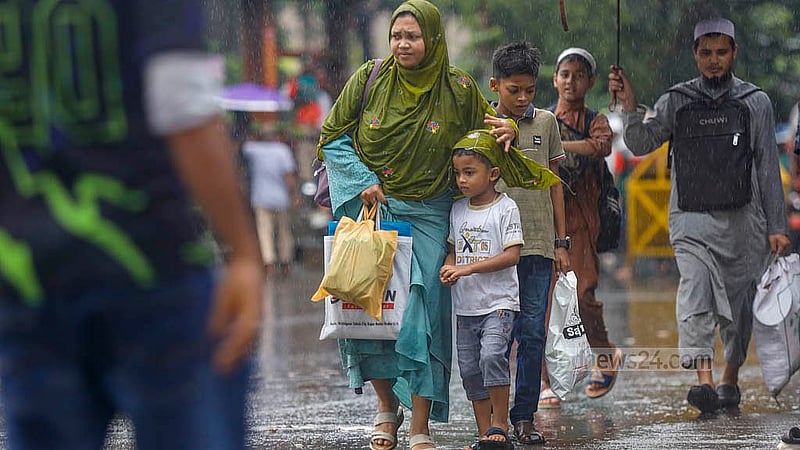 With relentless rain and a road blockade, people are left without any transport. A woman attempts to shield a child from the rain using her clothes to cover their head. Photo taken in Shahbagh, Dhaka, on Thursday, Jul 31, 2025. Photo: Mahmud Zaman Ovi.