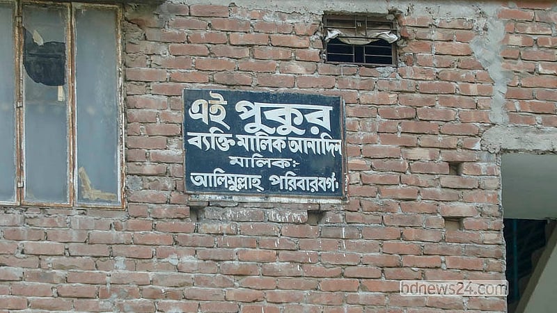 A family has put up a signboard on the wall of a nearby building, claiming ownership of the Sikkatuli Pond in Old Dhaka. Photo: Abdullah Al Momin