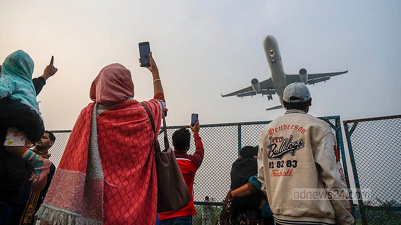 A family stands by the barbed-wire fence near the runway at Dhaka's Hazrat Shahjalal International Airport, watching planes take off and land. Photo: Mahmud Zaman Ovi