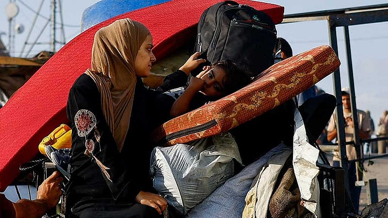 A displaced Palestinian woman and a child, fleeing northern Gaza due to an Israeli military operation, sit on a vehicle packed with belongings after evacuating southwards following Israeli forces' orders to leave Gaza City, in the central Gaza Strip, Sept 23, 2025. REUTERS